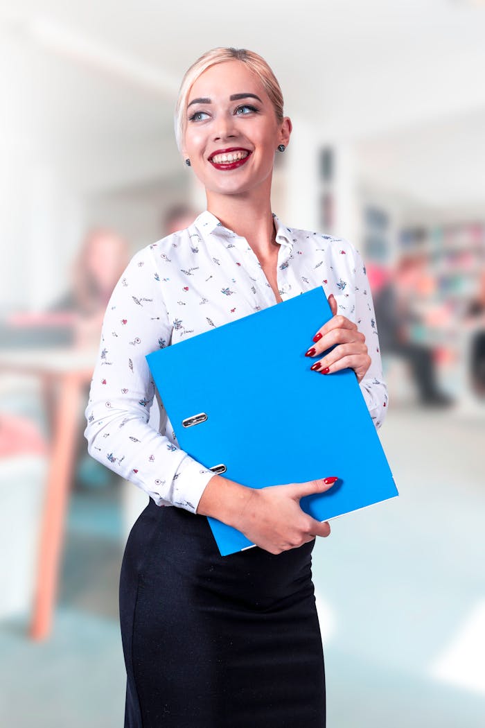 why-choose-us Confident businesswoman in a bright office holding a blue binder and smiling.